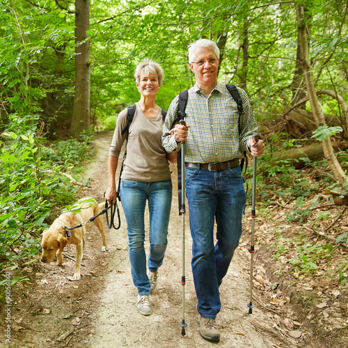Zwei Senioren wandern mit Hund im Wald