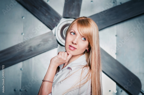 Photography Portrait of beautiful young dreamy woman with a big propeller on a steely wall b