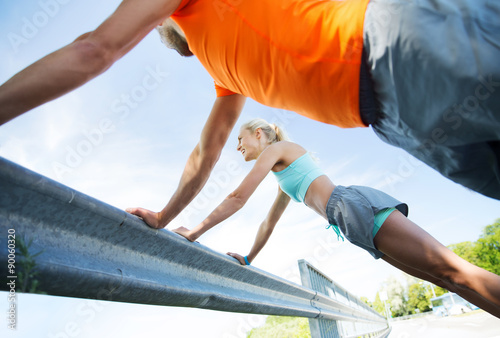 close up of happy couple doing push-ups outdoors