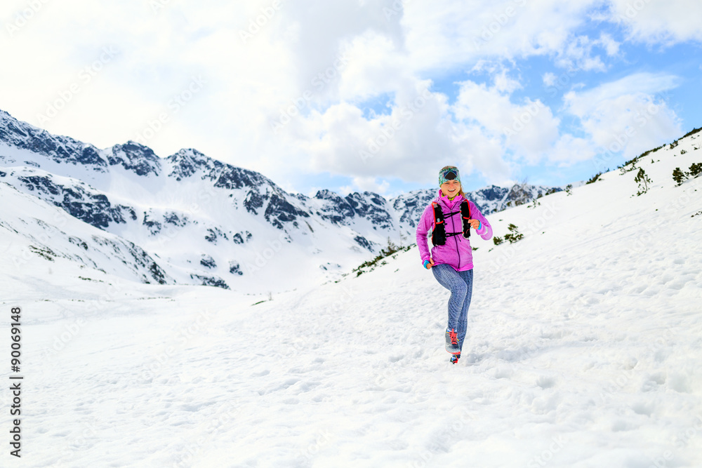 Woman running in mountains in inspirational winter landscape