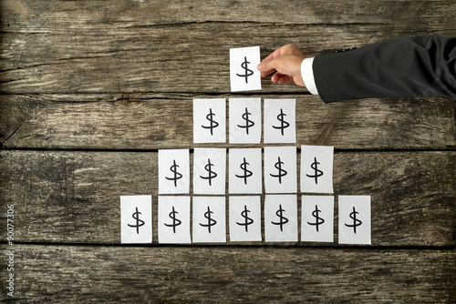 Canvas Print Overhead view of businessman arranging dollar sign in pyramid shape
