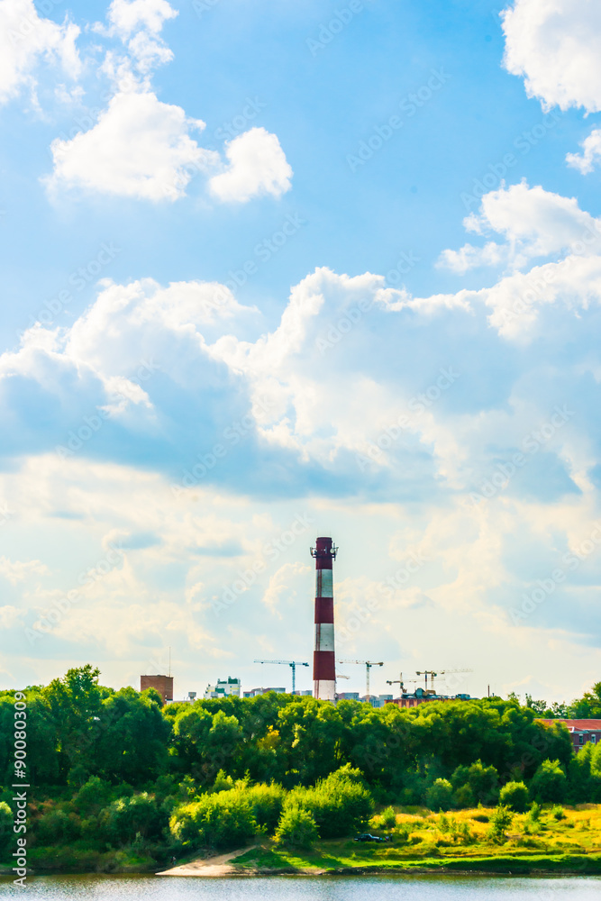 Obraz premium Industrial landscape with clouds and greenery.