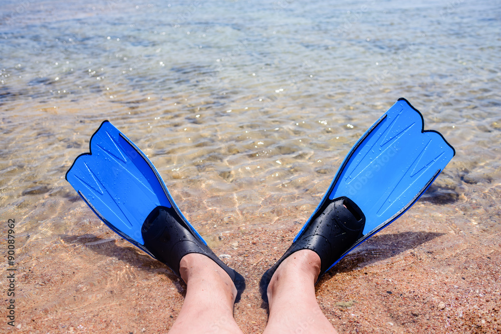 Person wearing fins lying at the edge of the sea Person wearing fins lying at the edge of the sea