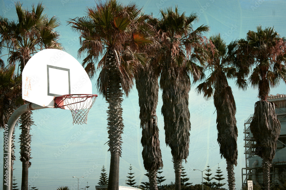 Naklejka premium aged and worn vintage photo of basketball hoop at beach with palm trees