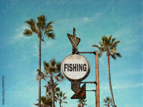 aged and worn vintage photo of fishing sign at beach