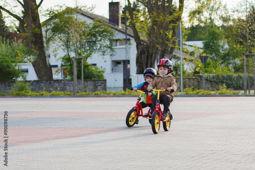 Two little siblings having fun on bikes in city on vacations