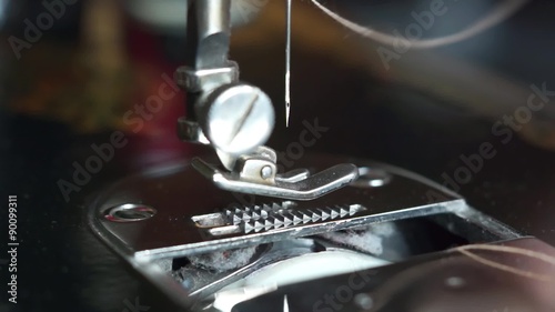 The woman inserts a light thread in a needle of the sewing machine
