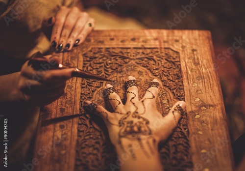 Drawing process of henna menhdi ornament on woman's hand photo