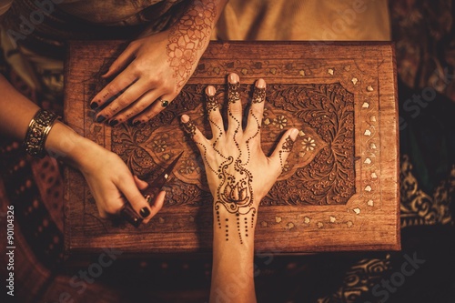Drawing process of henna menhdi ornament on woman's hand photo