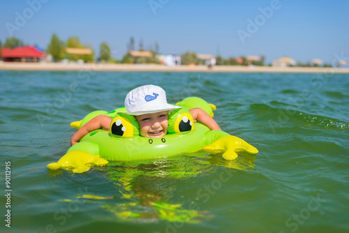 Little happy boy swimming at sea with rubber ring. photo