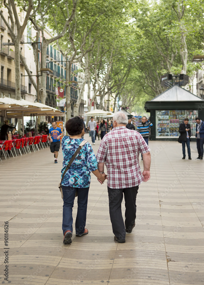 Obraz premium An older couple walking in the narrow streets of Barcelona, Spain