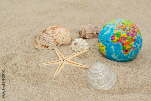 Globe with shells and sea star on sand