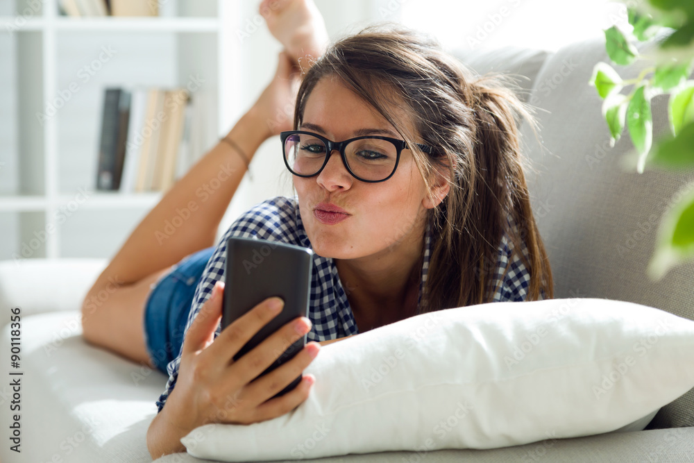 Beautiful young woman using her mobile phone at home. Beautiful young woman using her mobile phone at home.
