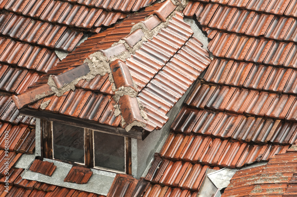 Part of the roof of old townhouse with wet from rain tiles