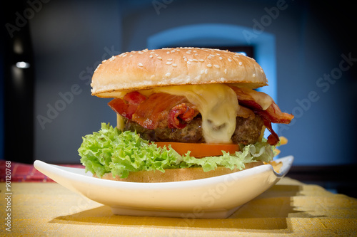 Hamburger is one of the most popular food not only on the street, but also in restaurant. Сочный гамбургер на тарелке.