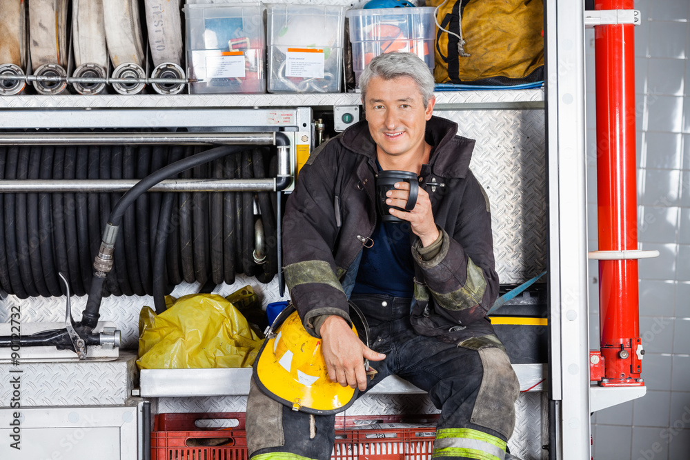Fototapeta premium Smiling Fireman Sitting In Truck At Fire Station