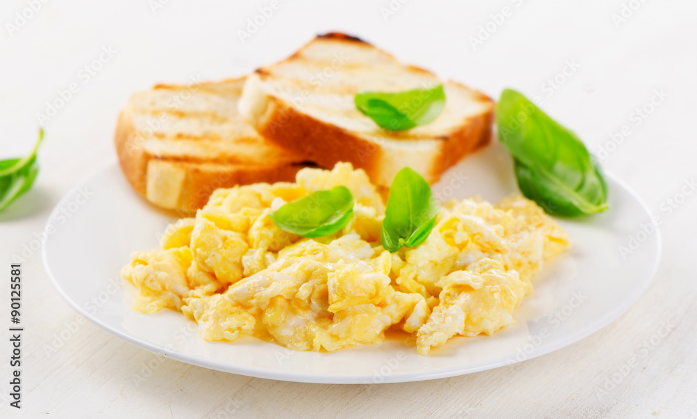 Scrambled eggs and toasts with basil.