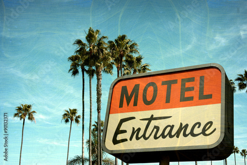 aged and worn vintage photo of motel entrance sign with palm trees