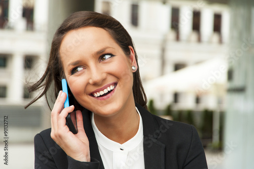 Foto Business woman talking by phone against the glass wall in the ci
