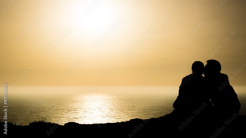 loving couple sitting arm in arm at Portugals cliff coast