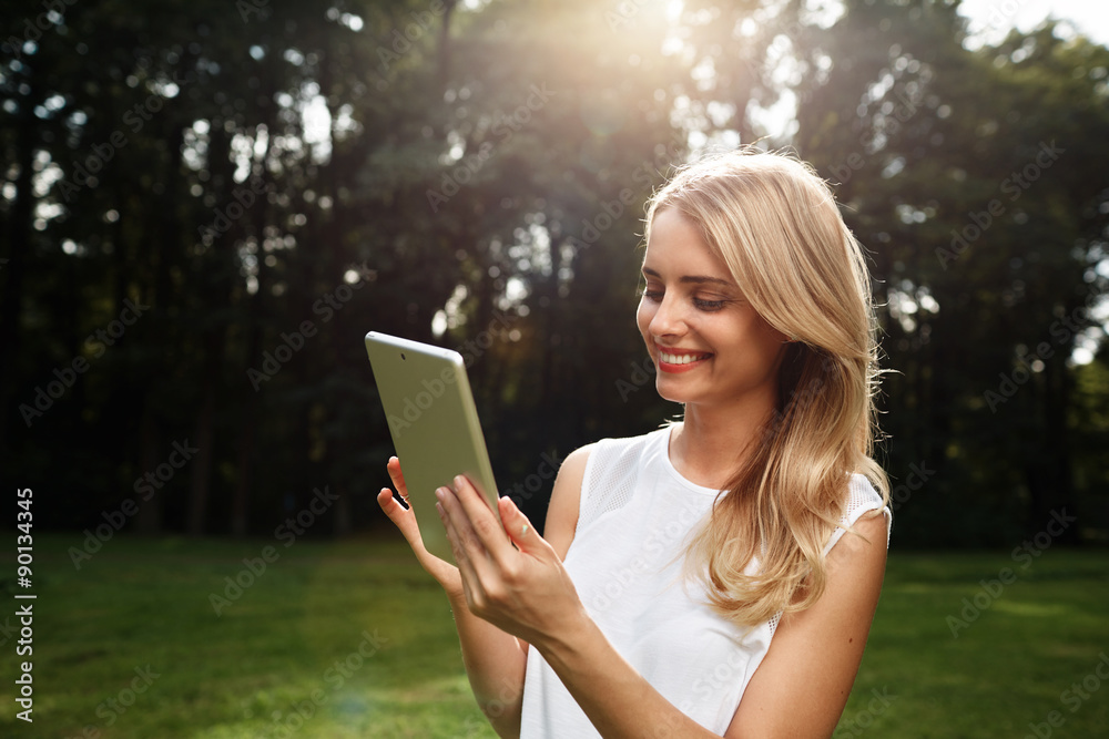 Closeup portrait of happy young blonde woman using tablet pc in Closeup portrait of happy young blonde woman using tablet pc in