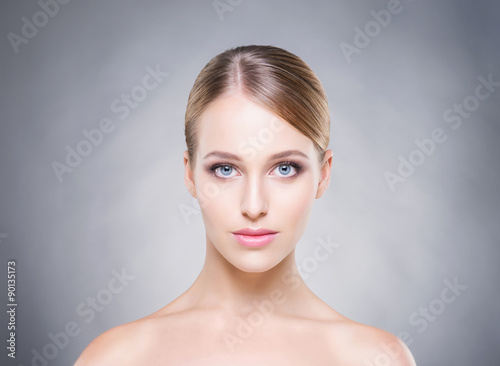 Beautiful and young woman over the grey background. Healthy skin.