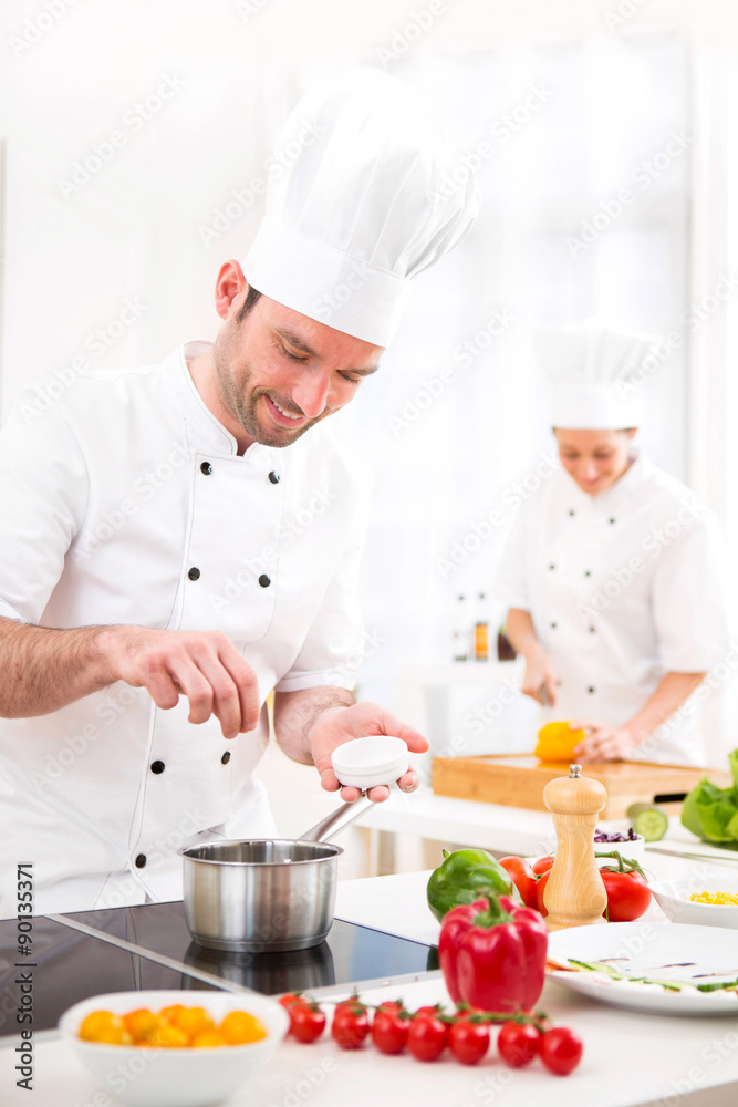 Young attractive professional chef cooking in his kitchen