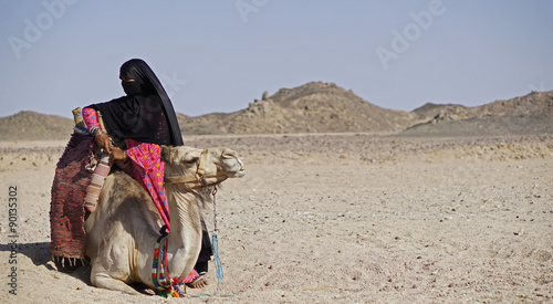 A bedouin woman minding her camel in the desert in Egypt. 