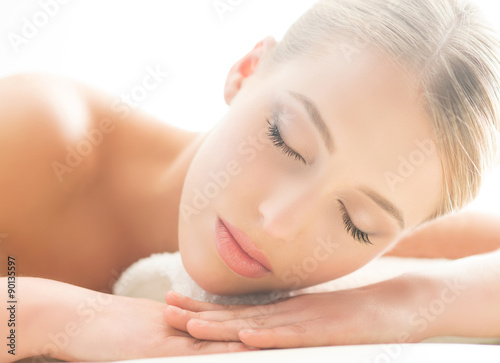 Beautiful young woman having leisure lying in a mat in spa.