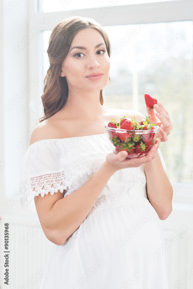 Beautiful pregnant woman with a bowl of strawberries. Beautiful pregnant woman with a bowl of strawberries.