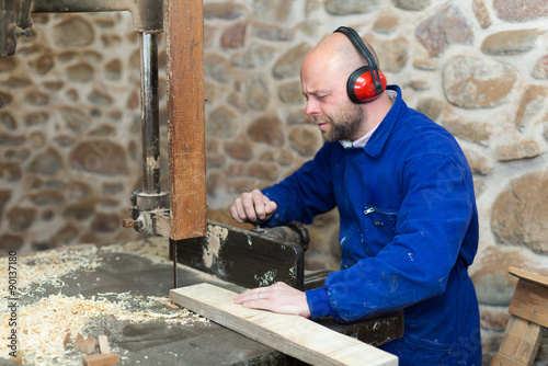 Man working on a machine at wood workshop.