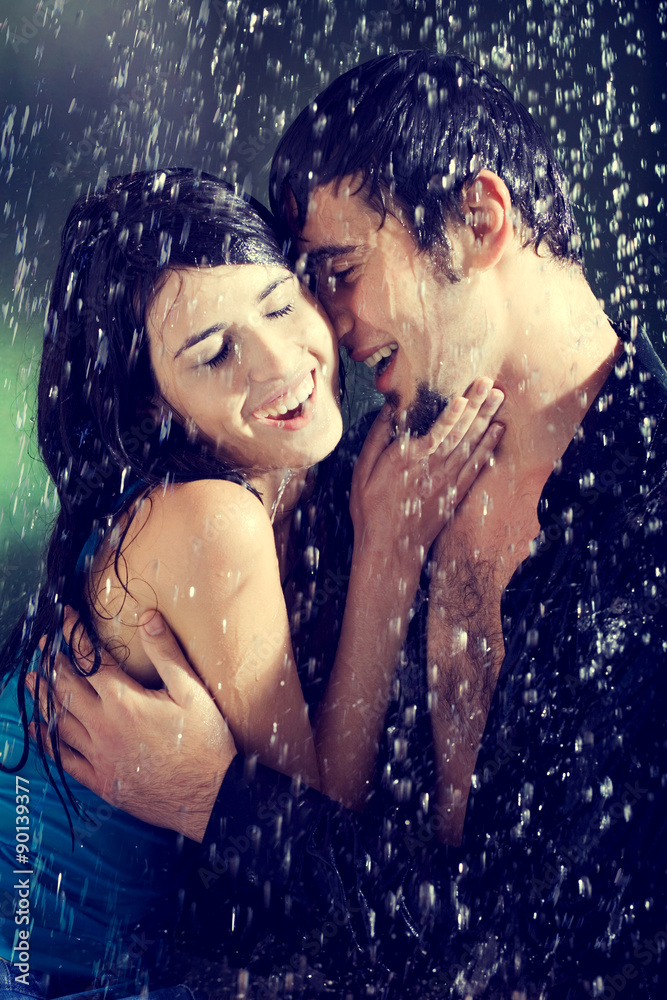 Obraz premium Young couple hugging and under a rain, in passion