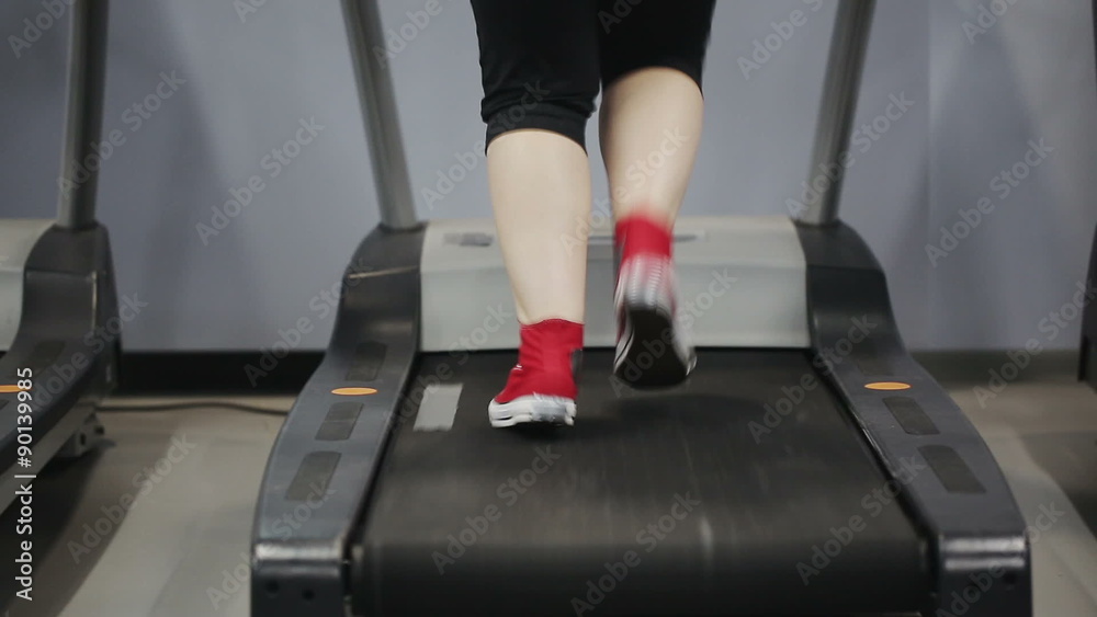 Close up woman's legs in red sneakers on a treadmill in the gym. Slider camera movement left to right Close up woman's legs in red sneakers on a treadmill in the gym. Slider camera movement left to right