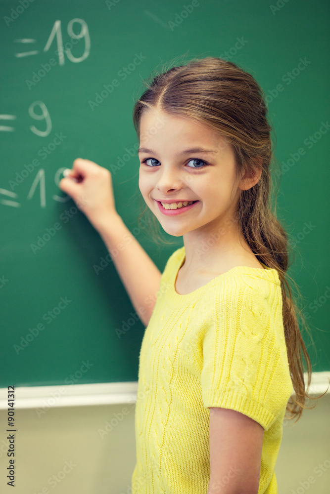 little smiling schoolgirl writing on chalk board little smiling schoolgirl writing on chalk board