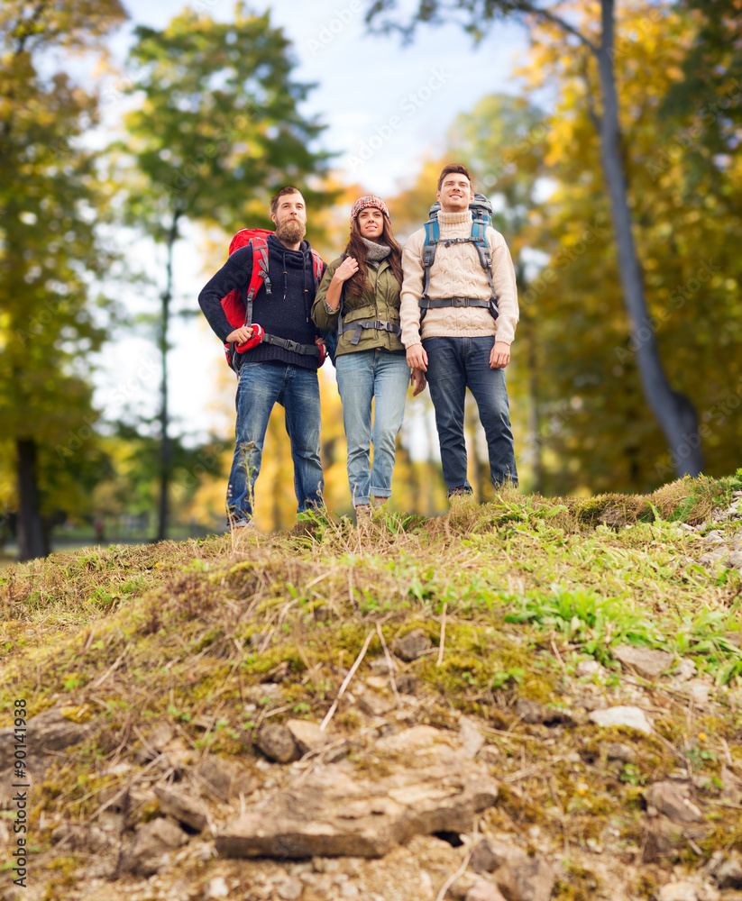 group of smiling friends with backpacks hiking