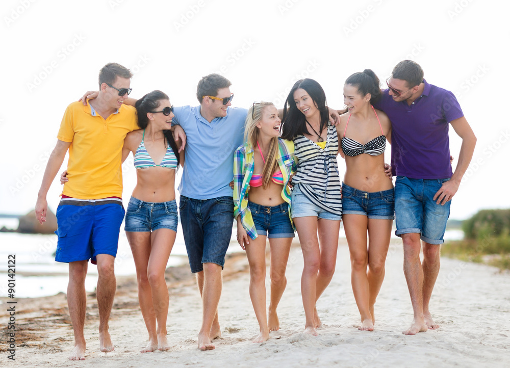 group of happy friends walking along beach group of happy friends walking along beach