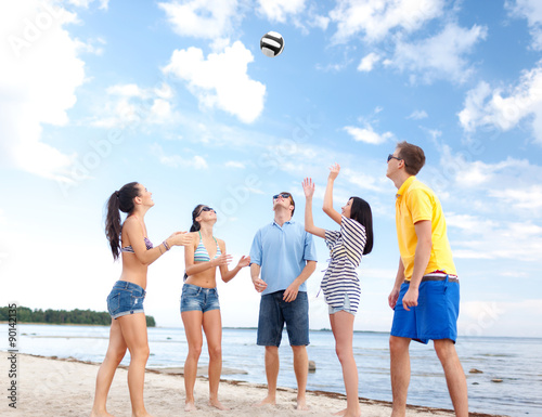 group of happy friends playing beach ball