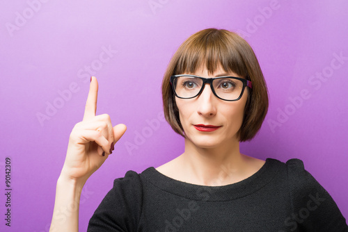 portrait of a woman with glasses forefinger up