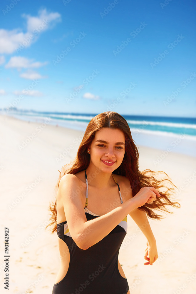 Portrait of confident woman in sexy bikini running on beach
