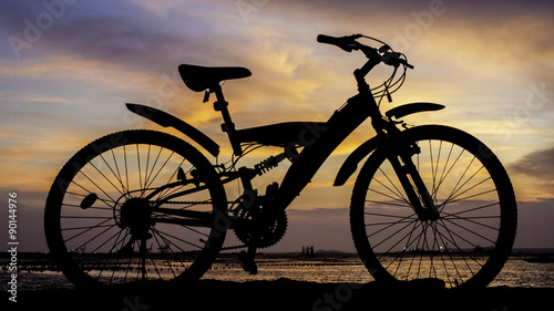 Silhouette of mountain bike with sunset sky beside sea
