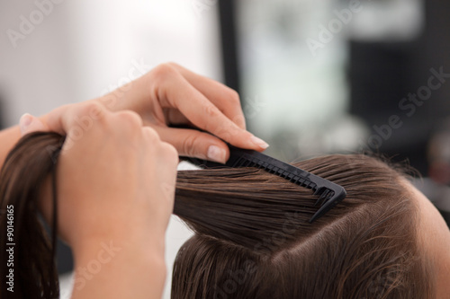 Professional young hairdresser is working with a comb