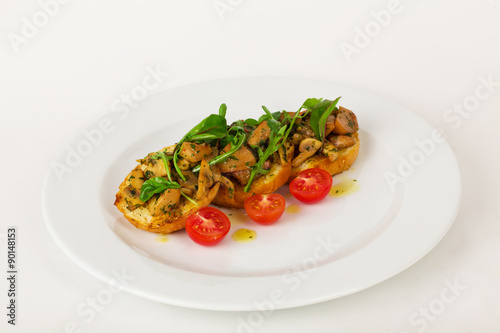Bruschetta with mushrooms and cherry tomatoes basil on a plate isolated for the menu