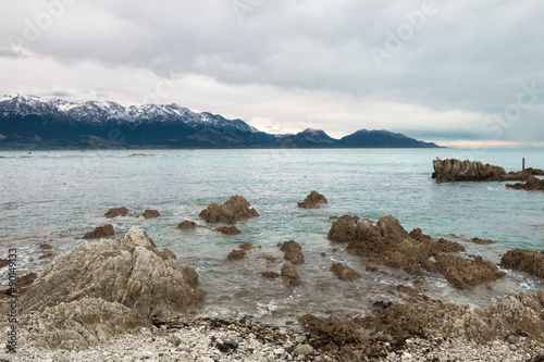 Snow covered mountains on ocean shore, Kaikoura, New Zealand photo