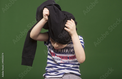 Boy changing his sweatshirt, but it's stuck on his head.