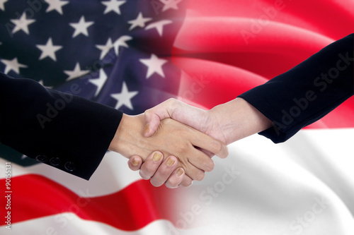 Workers handshake with the american and indonesian flags