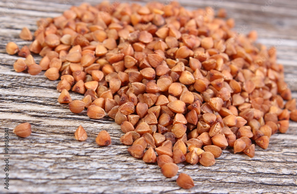 Heap of buckwheat groats on wooden surface Heap of buckwheat groats on wooden surface