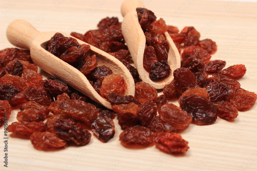 Brown raisins with spoon on wooden table, healthy eating Brown raisins with spoon on wooden table, healthy eating