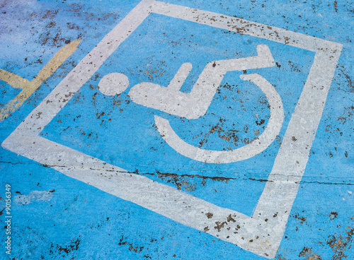 Handicapped parking sign on the road is quite old.
