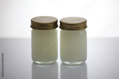 Pain relief balm in glass, white background.
