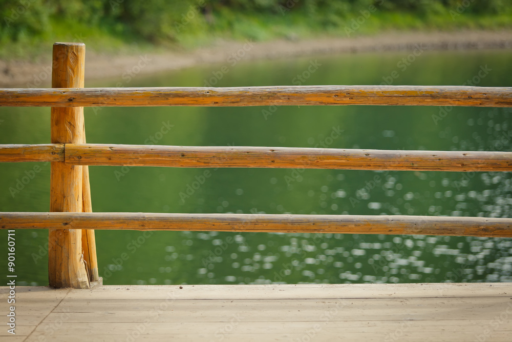 wooden railing against blue lake